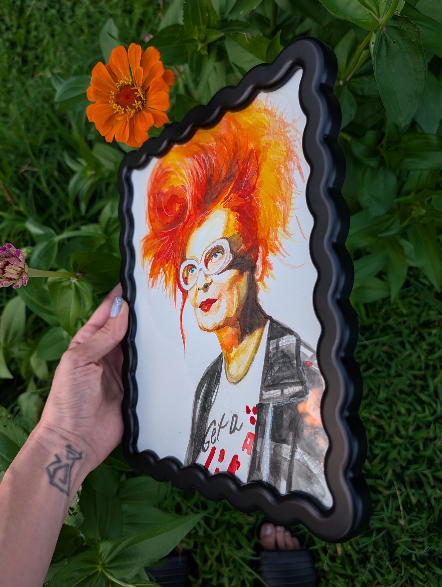 Original mixed media portrait of Vivienne Westwood with orange red hair white glasses and Get a Life Foundation shirt in black wavy frame