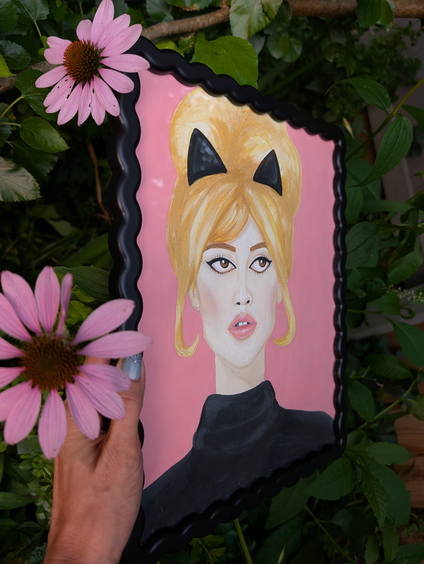 Original mixed media portrait of Brigitte Bardot with black cat ears and black turtleneck on pink background in black wavy frame