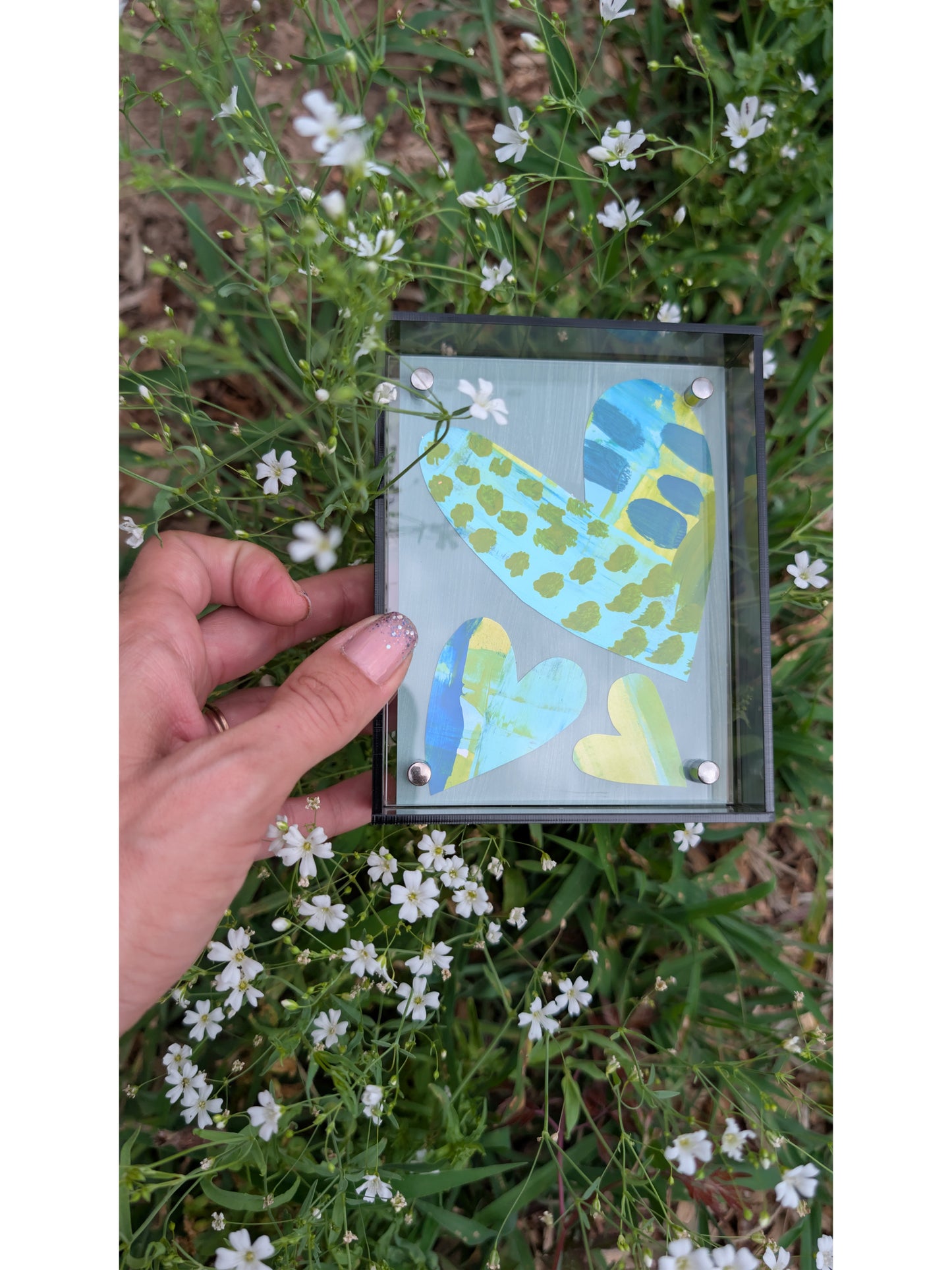Small original heart collage with blue turquoise and green hand-painted paper hearts on gray background in gray acrylic float frame