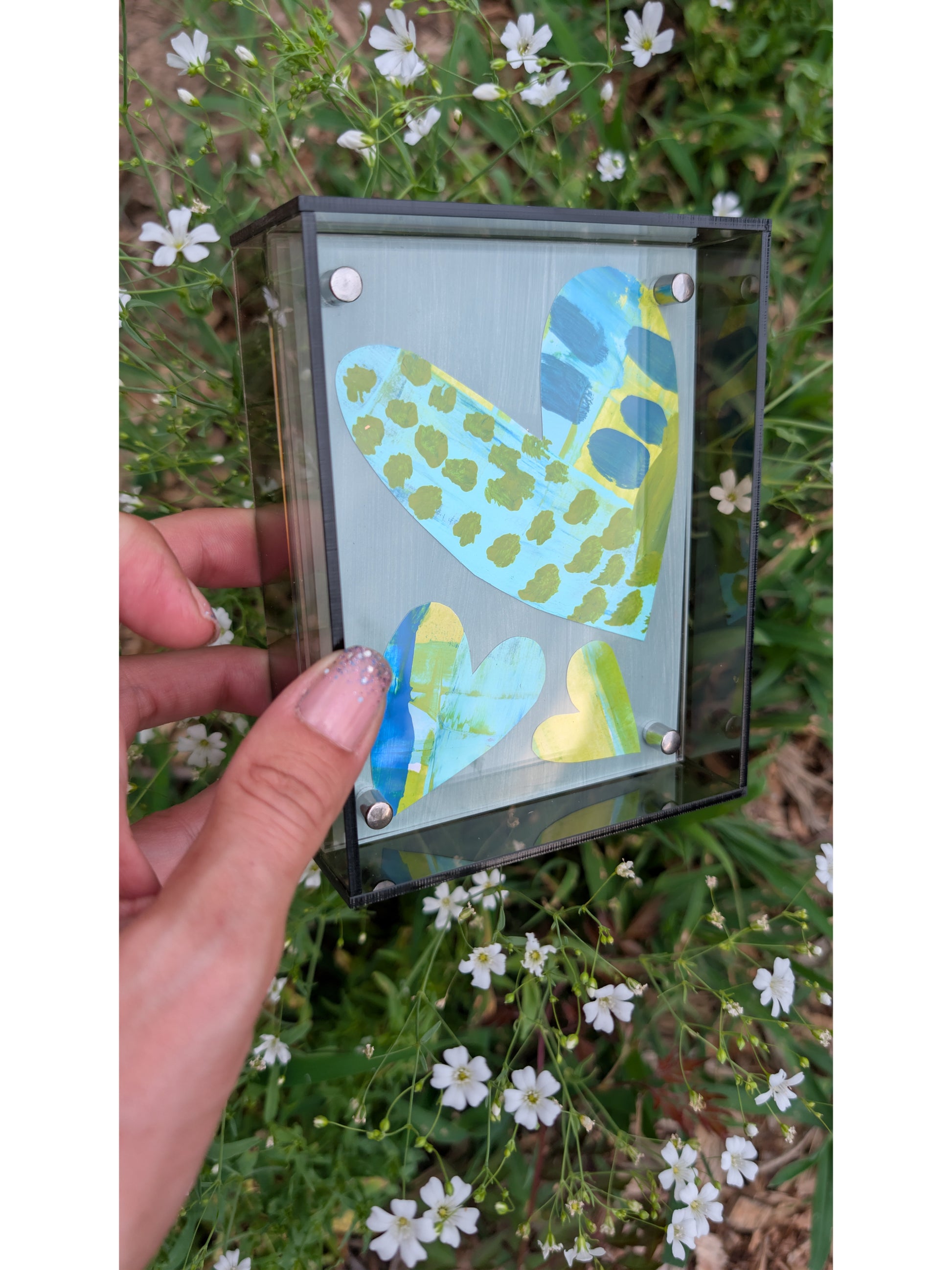 Small original heart collage with blue turquoise and green hand-painted paper hearts on gray background in gray acrylic float frame