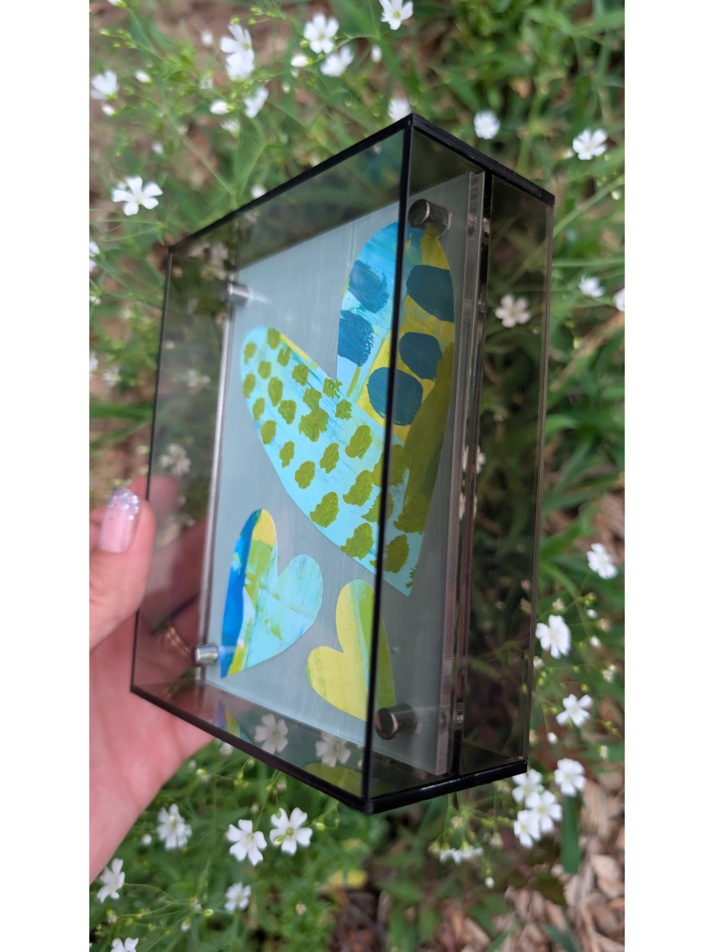 Small original heart collage with blue turquoise and green hand-painted paper hearts on gray background in gray acrylic float frame