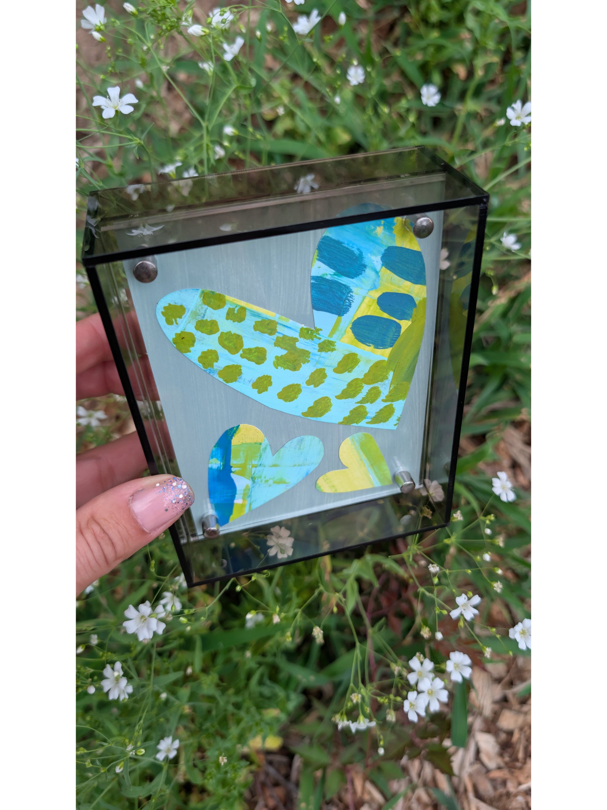 Small original heart collage with blue turquoise and green hand-painted paper hearts on gray background in gray acrylic float frame